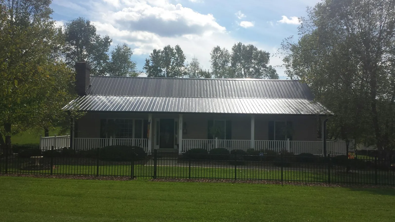 Gray metal roof on a brick ranch with a full width front porch — Gutter Guard Installation work by our crew in Shady Valley