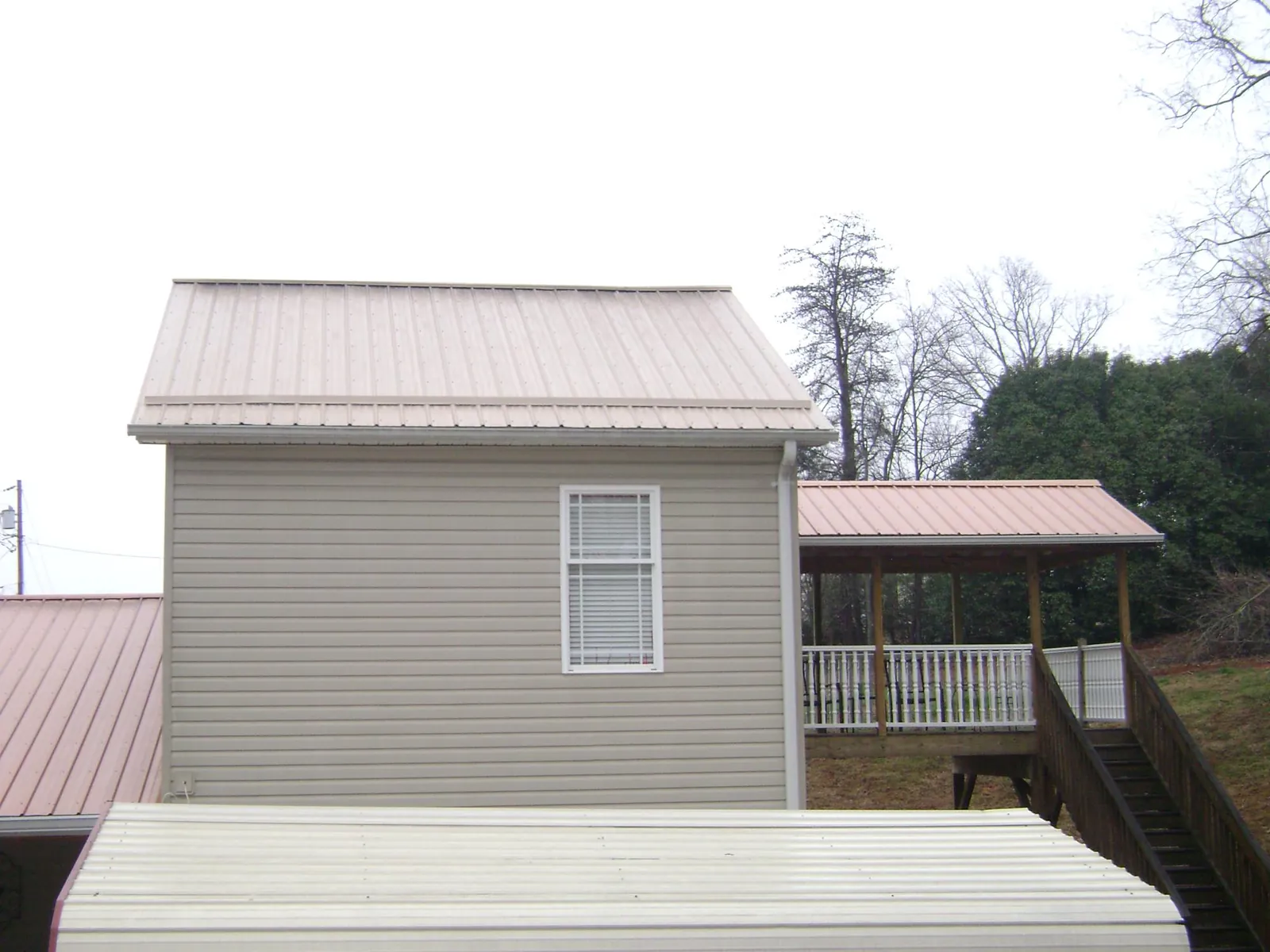 Tan metal roofs on a two story addition and attached porch, from a Roof Replacement job in Shady Valley