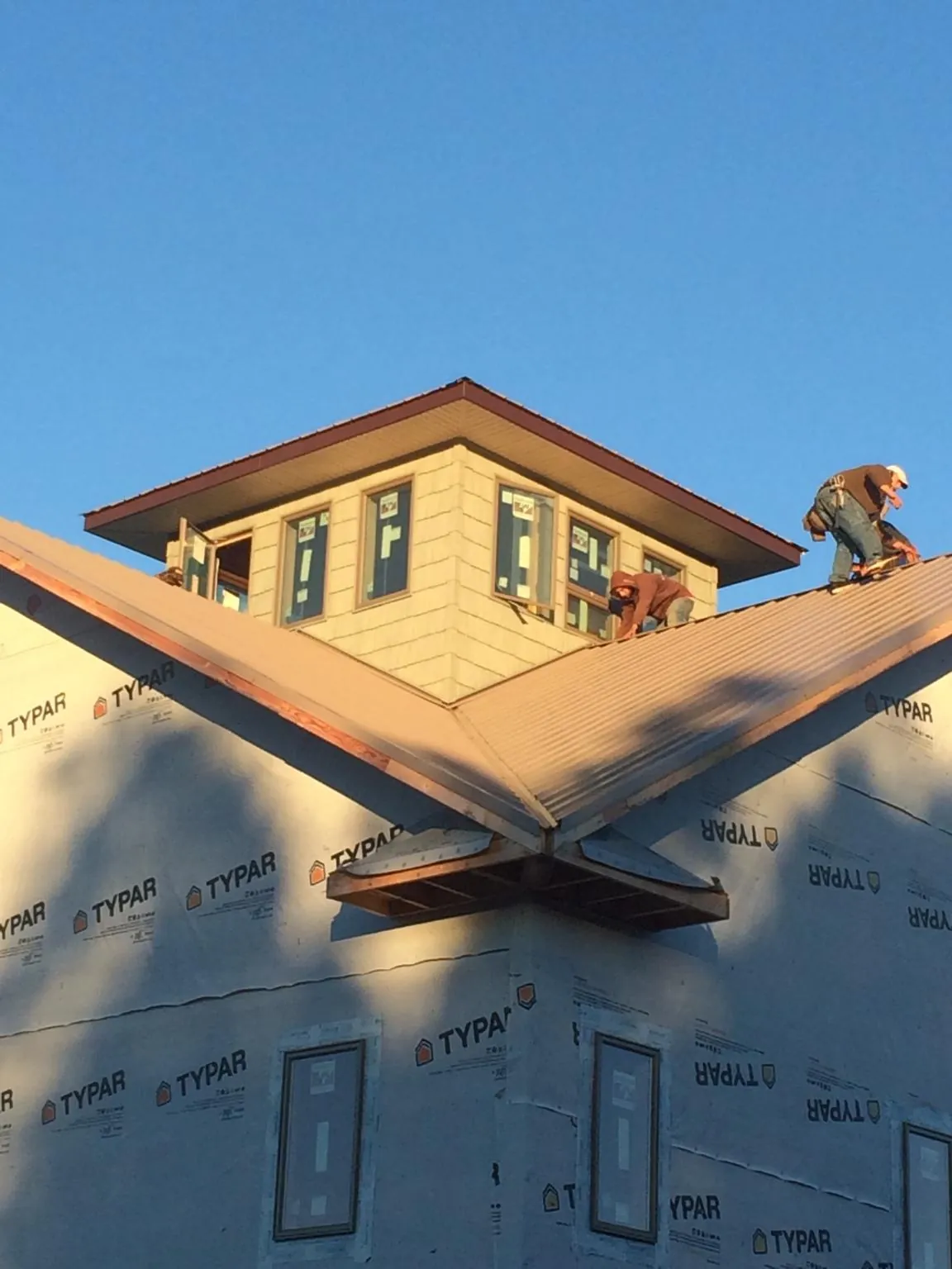 Roofers working around a rooftop cupola on a new metal roof at sunset — Roof Waterproofing in Shady Valley by Roofing Brothers